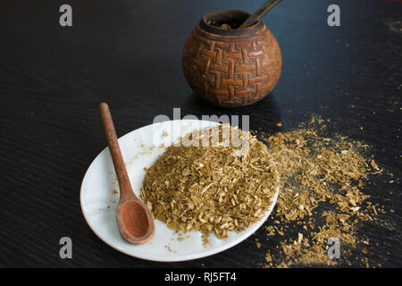 Künstlerische Fotografie der yerba mate Infusion, typische aus Argentinien, in eine weiße Platte, über einen dunklen Hintergrund Stockfoto