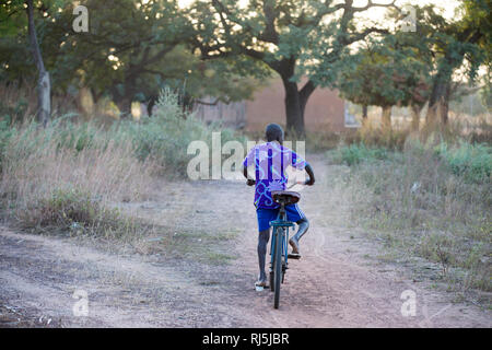 Bodadiougou Dorf, Banfora, Cascades Region, Burkina Faso, 4. Dezember 2016; EIN Junge auf seinem Fahrrad durch den Ort. Stockfoto