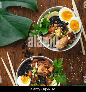 Asiatische Lebensmittel Konzept. Poke Schüssel mit gebratener Reis, Huhn und Eier, Ansicht von oben Stockfoto