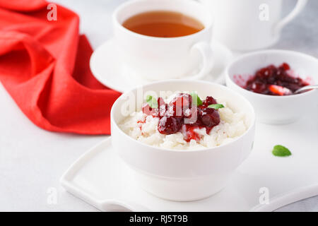 Gesundes Frühstück Konzept mit reisbrei serviert mit Cranberry Konfitüre und frischer Minze. Stockfoto