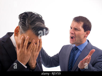 Zwei Geschäftsleute haben ein Argument vor einem ganz weißen Hintergrund: Ein Mann hat seinen Kopf in den Händen, der andere schreit ihn an. Stockfoto