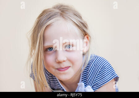 Süße kleine Mädchen im blauen Kleid Konsummilch und lächelnd im Freien Stockfoto