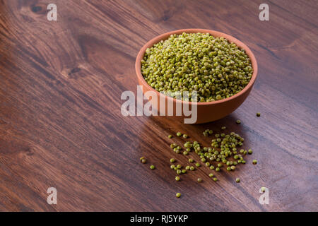 Frisches Grün Ausschreibung Sorghum in einem irdenen Schüssel auf Holz- Hintergrund Stockfoto