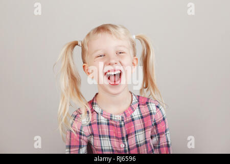 Closeup Portrait von cute adorable White blond Kaukasischen Vorschule Mädchen lächelnd vor der Kamera im Studio. Kind lachen auf normales Licht bac Posing Stockfoto