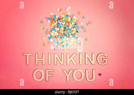 Happy Valentinstag. Schöne Karte mit Haufen von bunten Herzen Bonbons auf Rosa coral Hintergrund. Konzept der Liebe im Februar. Holz- worten Lett Stockfoto