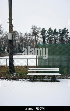 Verschneite Bank ein Zaun vor einem Fußballplatz im Winter, Stockfoto