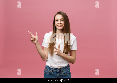 Foto der glückliche junge Frau stehen und poiting Finger über rosa Hintergrund isoliert. Stockfoto