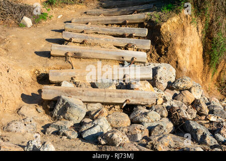 Alte verwitterte Treppe von Baumstämmen, der zum Strand führt, endet am Felsen Stockfoto