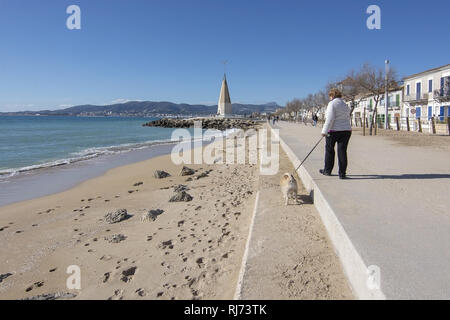 PALMA DE MALLORCA, SPANIEN - Februar 4, 2019: Frau geht kleiner Hund auf der Promenade in der Nähe von Molinar Turm mit blauem Himmel an einem sonnigen Tag, am 4. Februar 201 Stockfoto