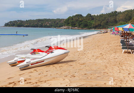 Rot und Weiß Yamaha Waverunner Jetskis am Strand vor bunten Sonnenschirme und Liegestühle in Surin Beach, West Coast Pkuket, Thailand Stockfoto