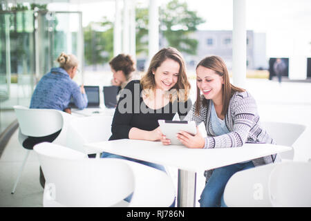 Zwei junge Frauen mit Tablette in einem Cafe Stockfoto