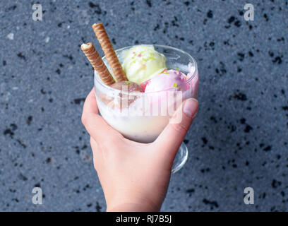 Hand mit einer Schale Eis mit gewalzten Wafer. eis Nahaufnahme. Stockfoto