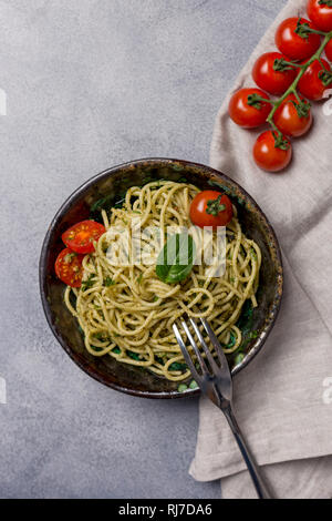 Pesto Pasta mit frischen Tomaten, die Schaltgabel und die Serviette auf grauen Hintergrund. Konzept der Italienisches Essen Stockfoto