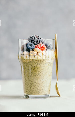 Chia Pudding mit Matcha Tee, Bio Müsli, gefrorene Beeren im Glas. Das Konzept der gesunden veganes Essen. Stockfoto