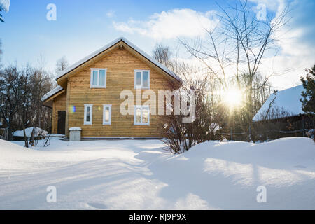 Holz- Haus in der russischen Landschaft im Winter. Es ist ein 2-stöckiges Haus mit Holz. Frosty sonnigen Tag. Stockfoto