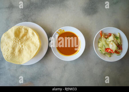Malaysische Street Food ein köstliches indisches Rezept für Beriayani und Roti Canai namens popodum, Curry und Acar auf Table Setup. Stockfoto