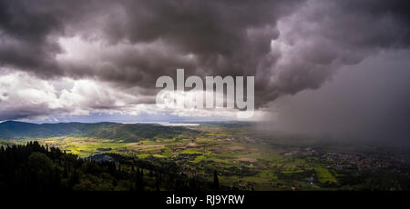 Luftaufnahme von Fortezza del Girifalco auf typische hügelige Landschaft der Toskana, dunkle Gewitterwolken anfahren Stockfoto