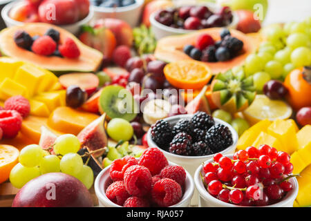 Gesund schneiden Obstteller Hintergrund Pflaumen Erdbeeren Himbeeren, Orangen, Äpfel, Kiwis, Weintrauben, rote Johannisbeeren Heidelbeeren mango Kaki Stockfoto