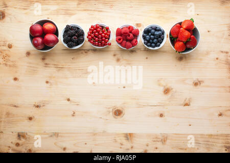 Blick von oben auf die gemischte Beeren in Schalen, Erdbeeren, Brombeeren, Blaubeeren Pflaumen rote Johannisbeeren Himbeeren, Kopie Raum Stockfoto