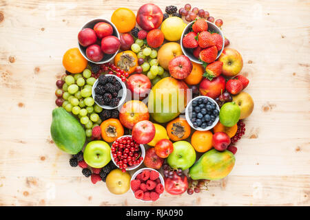 Rainbow Früchte Hintergrund Kreis Pflaumen Erdbeeren Himbeeren, Orangen, Äpfel, Kiwis, Weintrauben, Heidelbeeren mango Papaya auf Holztisch, Ansicht von oben Stockfoto