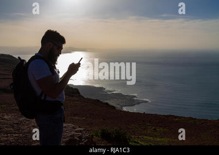 Der Mann Fotografien auf einer Insel im Ozean, stehen am Rand einer Klippe. Mirador del Rio, Lanzarote, Spanien. Stockfoto