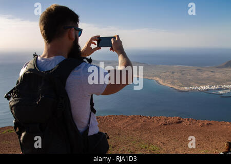 Der Mann Fotografien auf einer Insel im Ozean, stehen am Rand einer Klippe. Mirador del Rio, Lanzarote, Spanien. Stockfoto