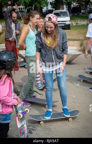 Eine weibliche Teenager skater lehrt ein junges Mädchen wie auf der Ebene Skatepark in Brighton, Sussex, UK zu skaten. Stockfoto