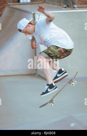 Ein junges Mädchen springt in die Luft, während Sie einen Trick beim Skaten in der Hove Lagune Skatepark, Hove, Brighton, England. Stockfoto