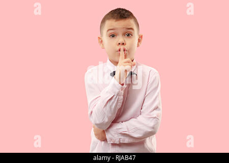 Geheimnis, Klatsch-Konzept. Jugendlich junge Flüstern ein Geheimnis hinter seiner Hand. Kind isoliert auf trendy Pink Studio Hintergrund. Menschliche Gefühle, Mimik Konzept. Stockfoto