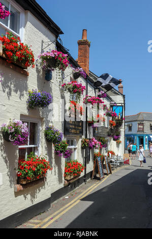 Beautiful​ Blüten in hängenden Körben und Töpfe auf der Wand des London Inn Pub in Padstow, Cornwall, England gefärbt. Stockfoto