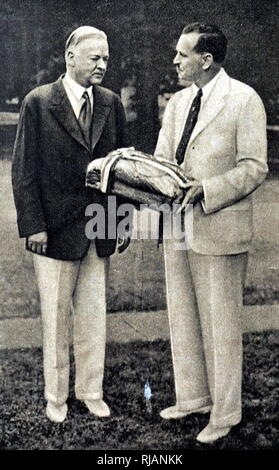 Foto von Präsident Herbert Hoover brechen Brot mit seinen olympischen Gast als Zeichen der Gastfreundschaft während der Olympischen Spiele 1932 in Los Angeles statt. 20. Präsident Herbert Hoover (1874-1964) ein US-amerikanischer Politiker und der 31. Präsident der Vereinigten Staaten von Amerika. Vom 20. Jahrhundert Stockfoto