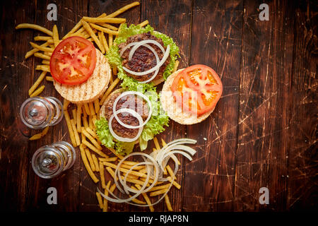 Zwei leckere gegrillte hausgemachte Burger mit Rindfleisch, Tomaten, Zwiebeln und Salat Stockfoto