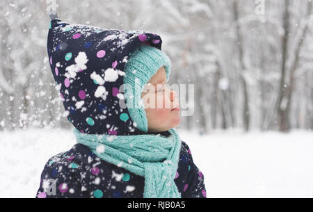 Baby im Winter jumpsuit freut sich über den ersten Schnee Stockfoto