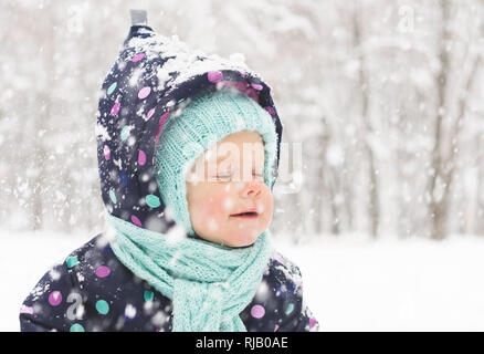 Baby im Winter jumpsuit freut sich über den ersten Schnee Stockfoto