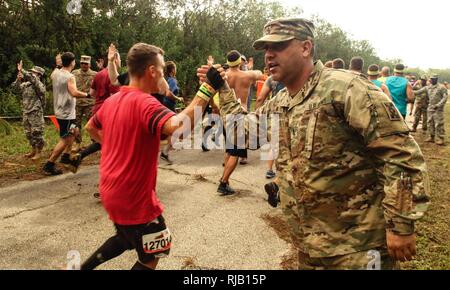 Armee Sgt. 1. Klasse Efrain Abreu, ein Motor Transport Operator in der 143 Sustainment Command (Auslandseinsätze) gibt eine haltbare Mudder Wettbewerber eine hohe fünf während der harten Mudder Herausforderung Nov. 5, 2016, in Palm Bay, Fla. Abreu, ein Eingeborener von Tampa, Fla., trat etwa 20 Soldaten der 143. WSA und der 196Th Transportation Company in der Unterstützung der Armee Marketing und Engagement für die Gemeinschaft der Arbeitsgruppe und Rekrutierung Initiativen in diesem internationalen Phänomen, das zieht jährlich Zehntausende von Menschen ihre physischen und psychischen Grenzen zu testen. Viele harte Mudder Stockfoto