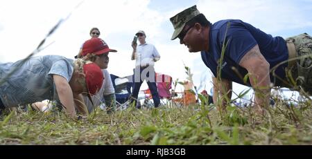 STUART, Fla (Nov. 6, 2016) - Chief Petty Officer Joseph Schmidt, die Navy SEAL und SWCC Scout Team zugeordnet sind, beteiligt sich an körperlichen Training mit jungen Fans an den 2016 Stuart AirShow. Die Scout Team betreibt Öffentlichkeitsarbeit für kommunale Gruppen und athletische Mannschaften über die Naval Special Warfare Training Mission zu informieren. Stockfoto