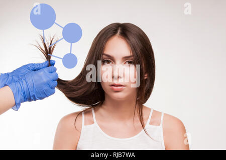 Master - Friseur Verfahren, Öl, Haarpflege für Frauen. Konzept Spa Salon. Der Arzt prüft die Struktur eines jungen Mädchens. Stockfoto