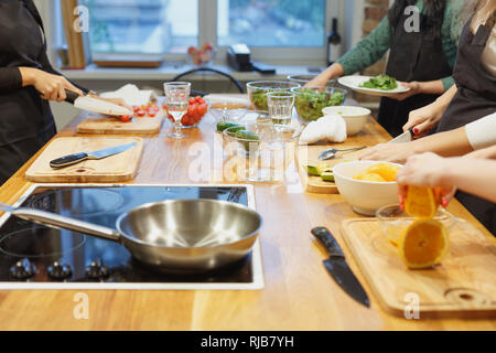 Multirassische lustige Freunde kochen einige geschmackvolle Lebensmittel in Küche und Wein trinken. Stockfoto