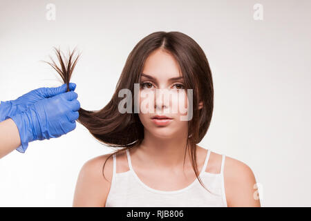 Master - Friseur Verfahren, Öl, Haarpflege für Frauen. Konzept Spa Salon. Der Arzt prüft die Struktur eines jungen Mädchens. Stockfoto