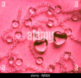 Transparente Herzen und Perlen auf Marmor in rosa Ton. Perfekte Valentinstag Grußkarte Hintergrund. Stockfoto