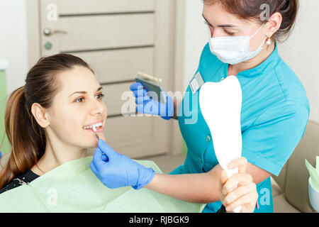 Schöne Zahnarzt Überprüfung und Auswahl der Farbe der Zähne der jungen Frau Stockfoto
