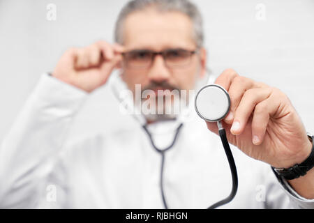 In der Nähe der Medizinischen Stethoskop. Hno-Arzt, Medizinische Geräte, mit einer Hand auf die Gläser. Arzt an Kamera suchen, im Studio posieren. Stockfoto