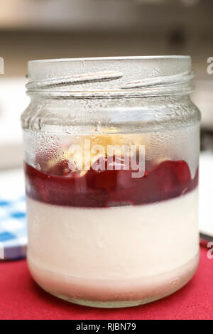 Panna Cotta Käsekuchen mit Sauerkirschen im Glas serviert. Stockfoto