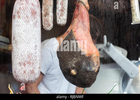 Nahaufnahme von Salami brötchen Würstchen hängen an String mit Schinken auf Anzeige in einem Markt shop Metzger mann Hintergrund Stockfoto