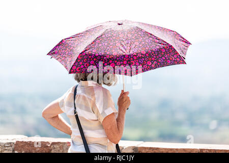 Assisi, Italien - 29 August 2018: Zurück Nahaufnahme von Menschen touristische ältere Frau mit rosa lila Sonnenschirm Schatten von Sun bei Anzeigen in Umbrien cit suchen Stockfoto