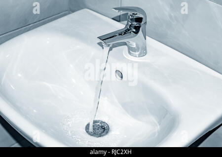 Waschbecken und Wasserhahn mit fließendem Wasser im Badezimmer. Stockfoto