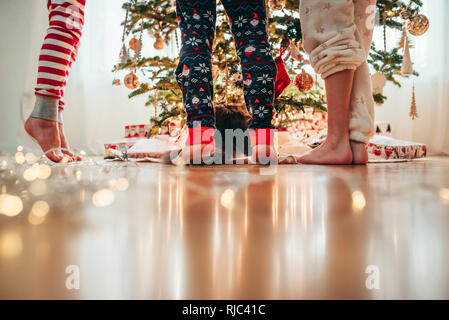 In der Nähe von drei Kindern Beine und eine Katze beim Dekorieren ein Weihnachtsbaum Stockfoto