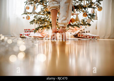 In der Nähe der Beine, ein stehendes Mädchen durch einen Weihnachtsbaum Stockfoto