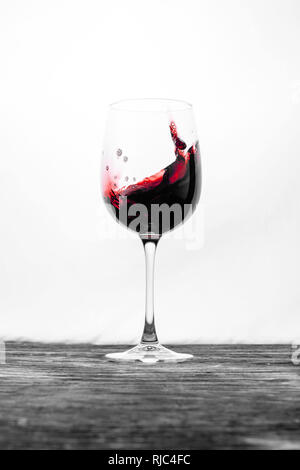 Der rote Wein im Glas spritzt in Bewegung auf einem weißen Hintergrund. Stilvolles Design drink Karte Stockfoto