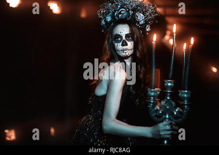 Frau mit Make-up für Halloween Leuchter mit brennenden Kerzen. Stockfoto